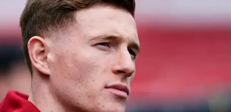 Player with short hair in red jersey looking away