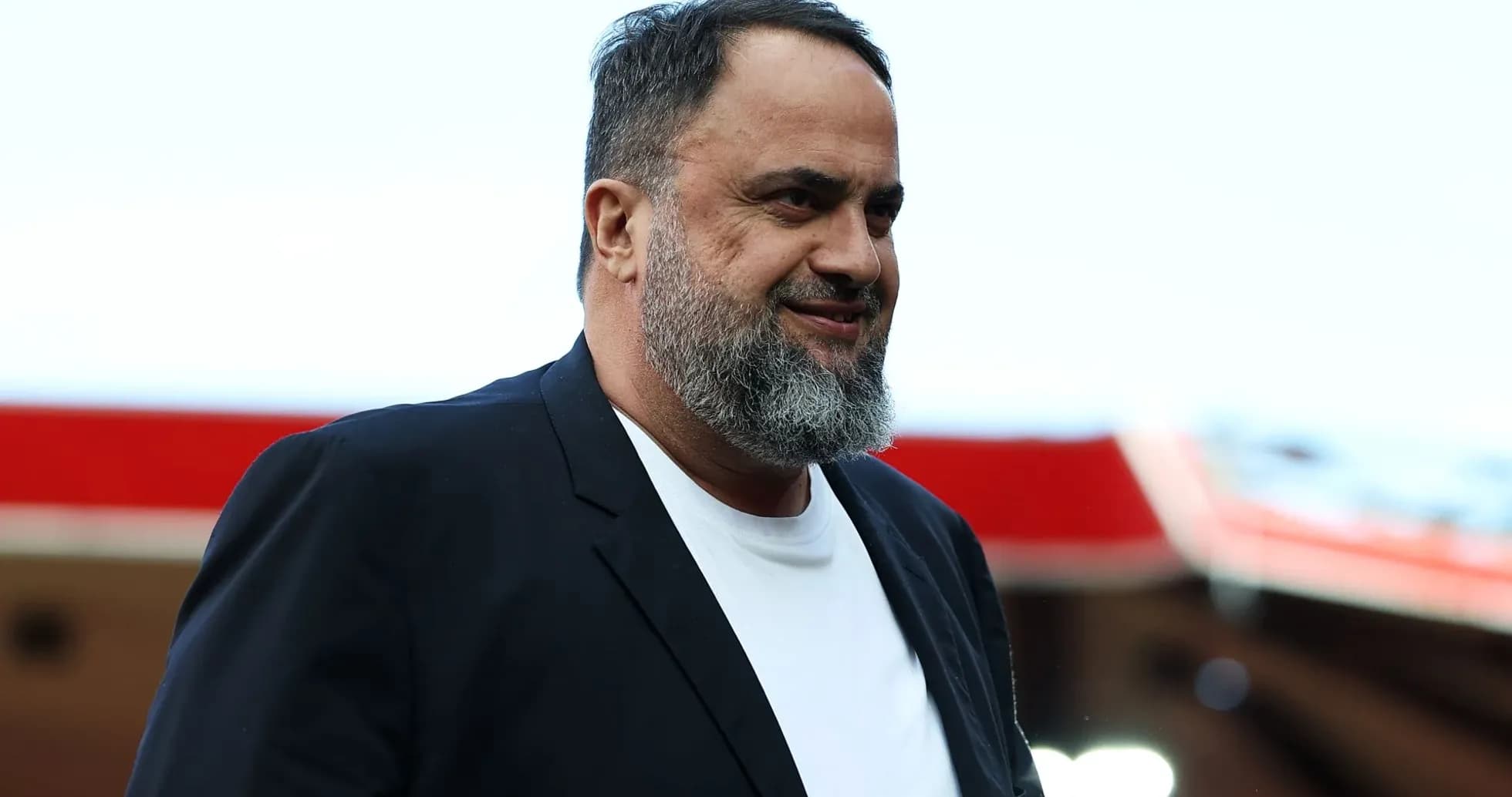 Man in blazer smiling at stadium entrance