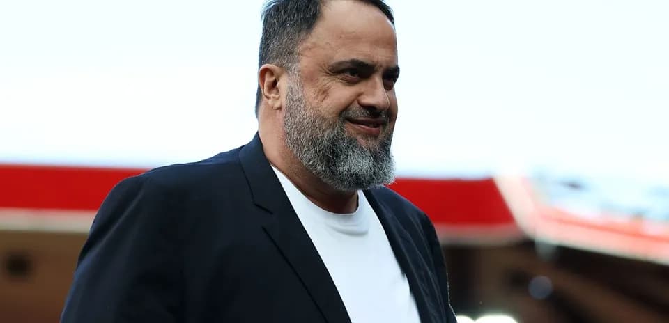 Man in blazer smiling at stadium entrance