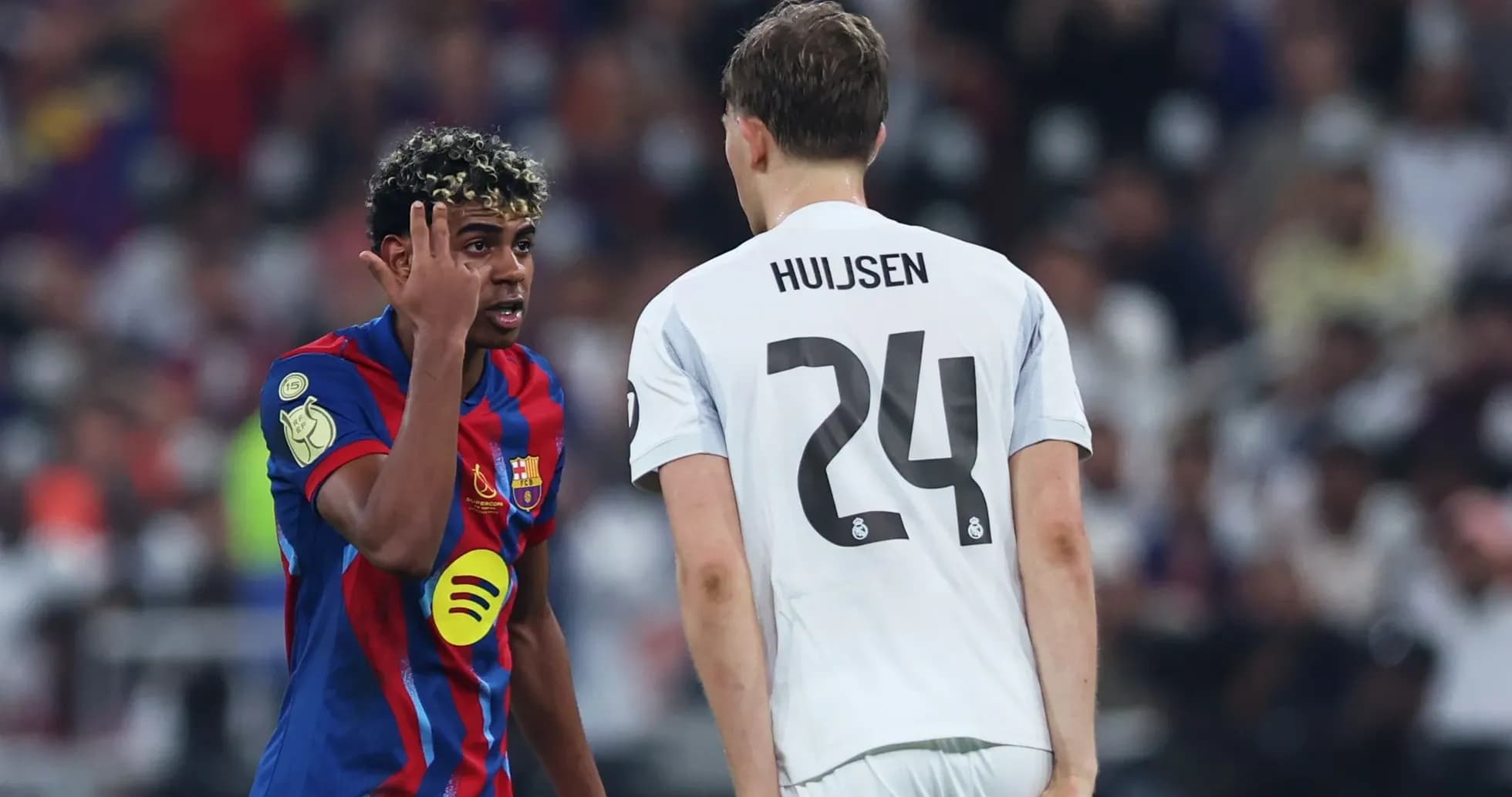 Barcelona player gesturing to Real Madrid opponent during match