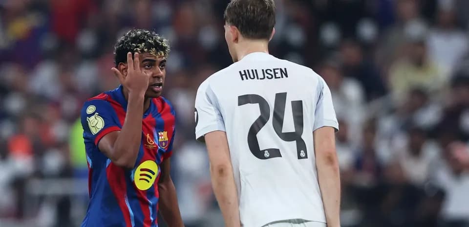 Barcelona player gesturing to Real Madrid opponent during match