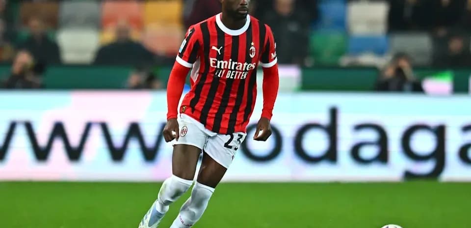 Player in AC Milan kit running with ball on field