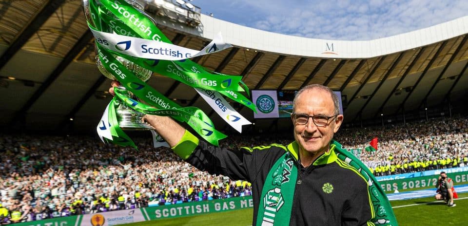 Man holding trophy with green ribbons in stadium
