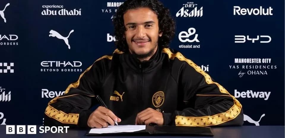 Player signing contract at press conference table
