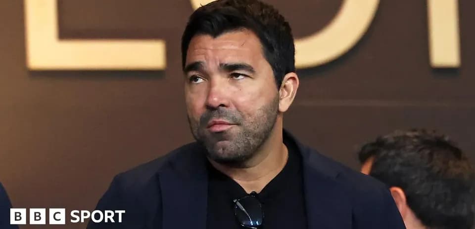 Man with dark hair in a suit looking away