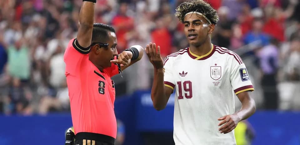 Referee signaling while player reacts during match
