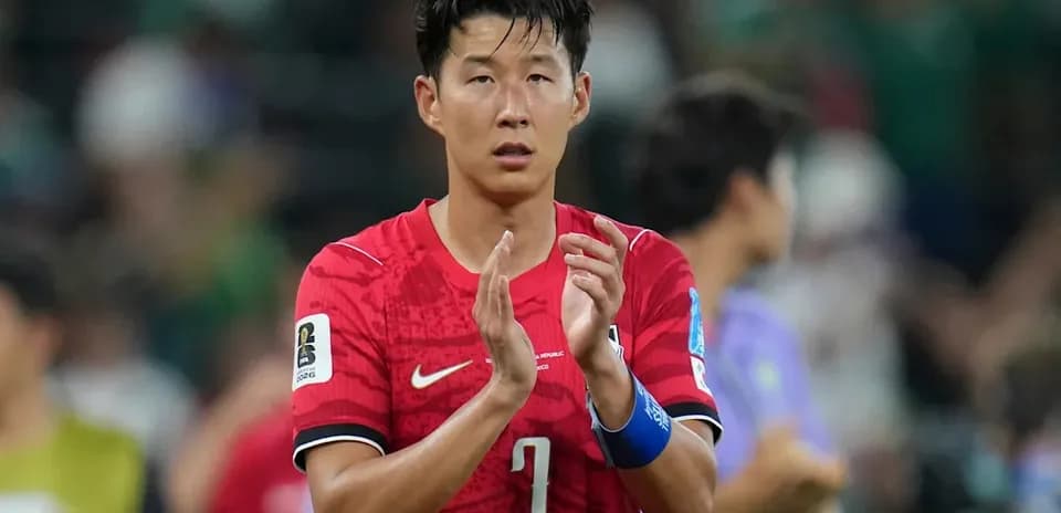 Player applauding fans after match in red jersey