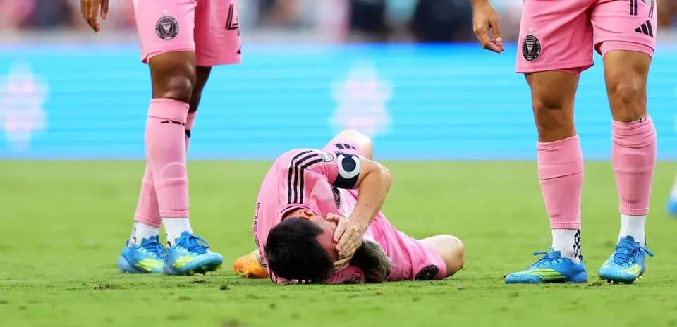 Player lying on field, teammates nearby in pink uniforms