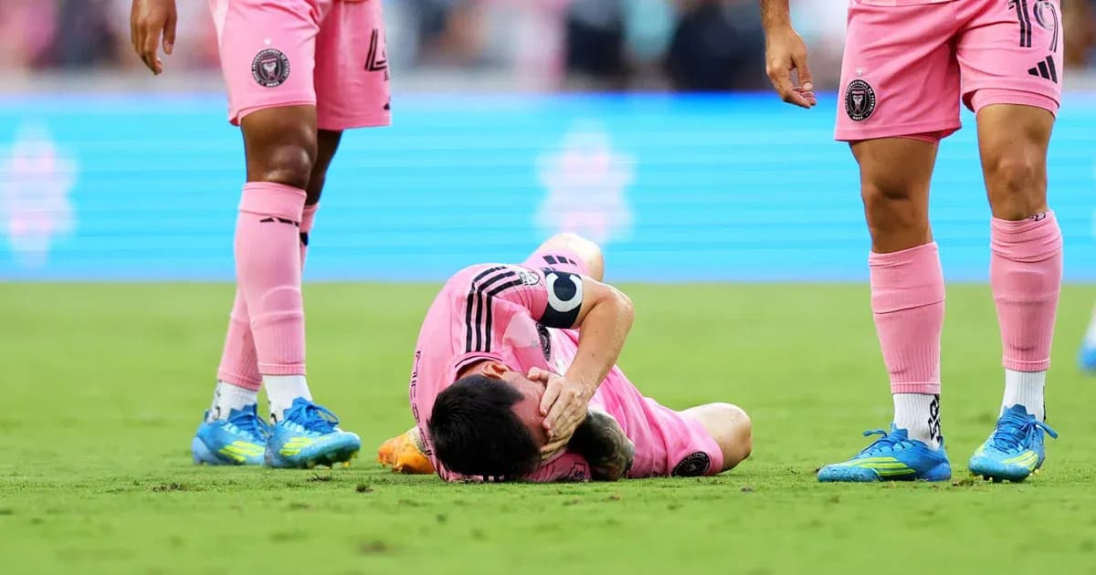 Player lying on field, teammates nearby in pink uniforms