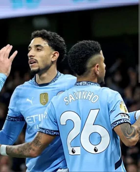Two Manchester City players celebrating on the pitch