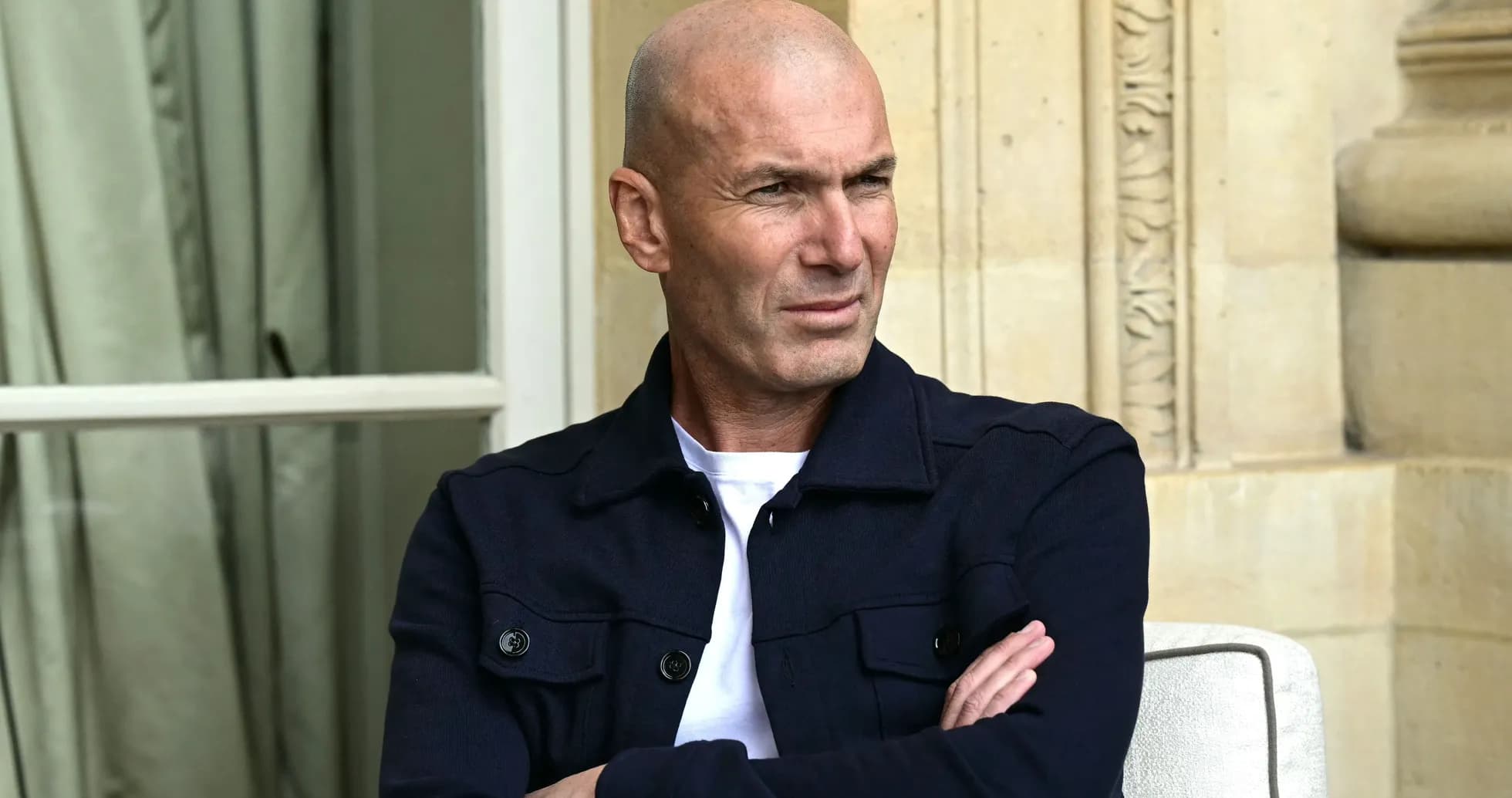 Man seated with arms crossed, outdoor setting