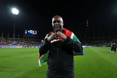 Coach holding South African flag on field