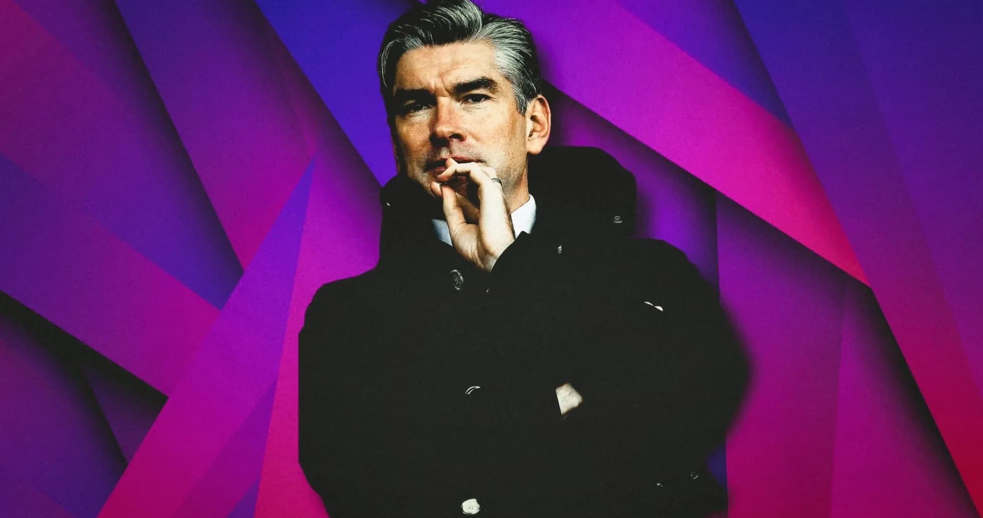 Man in a black coat against a colorful background