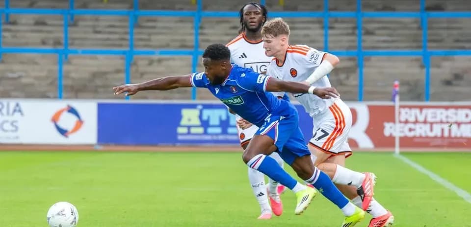 Player in blue shirt attempting to evade two defenders