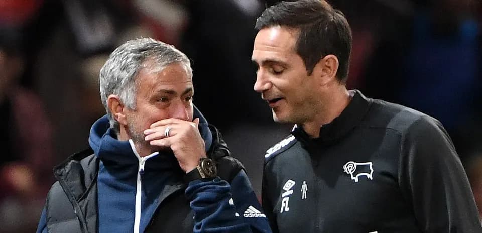 Two football managers conversing on the sidelines