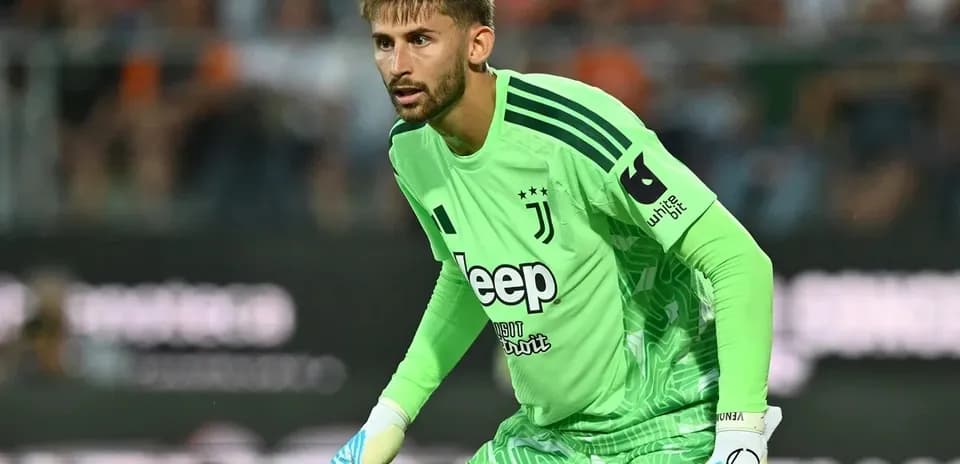 Goalkeeper in green jersey preparing to defend goal