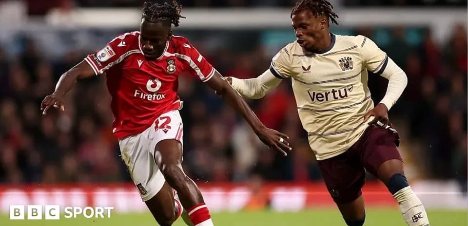 Player in red jersey dribbling past opponent in beige jersey