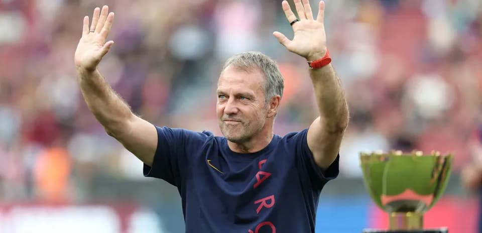 Coach waving to fans beside trophy at stadium