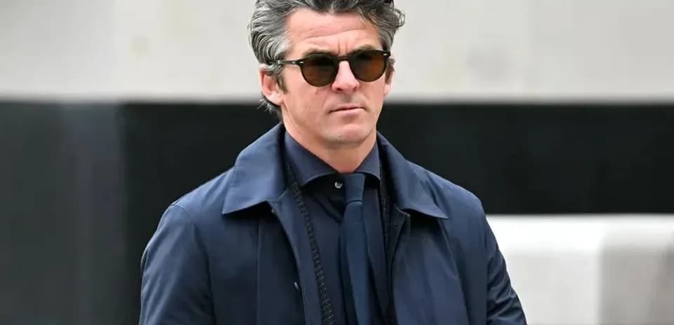 Man in sunglasses wearing a dark coat outdoors