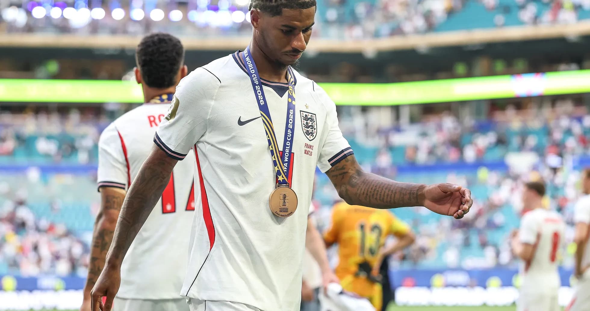 Player walking off field with bronze medal after match