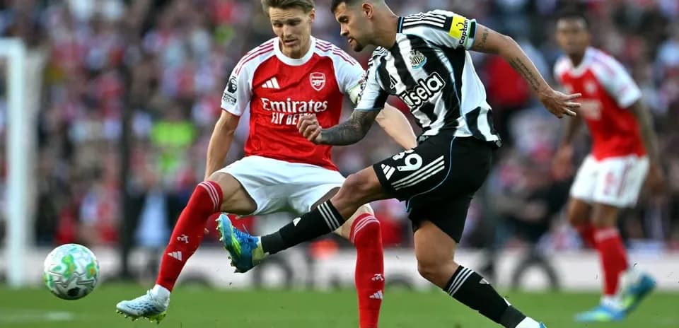 Newcastle player kicking ball past Arsenal defender
