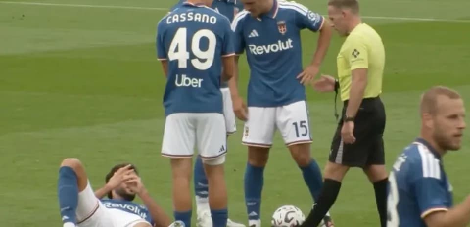 Player lying on ground with teammates and referee nearby