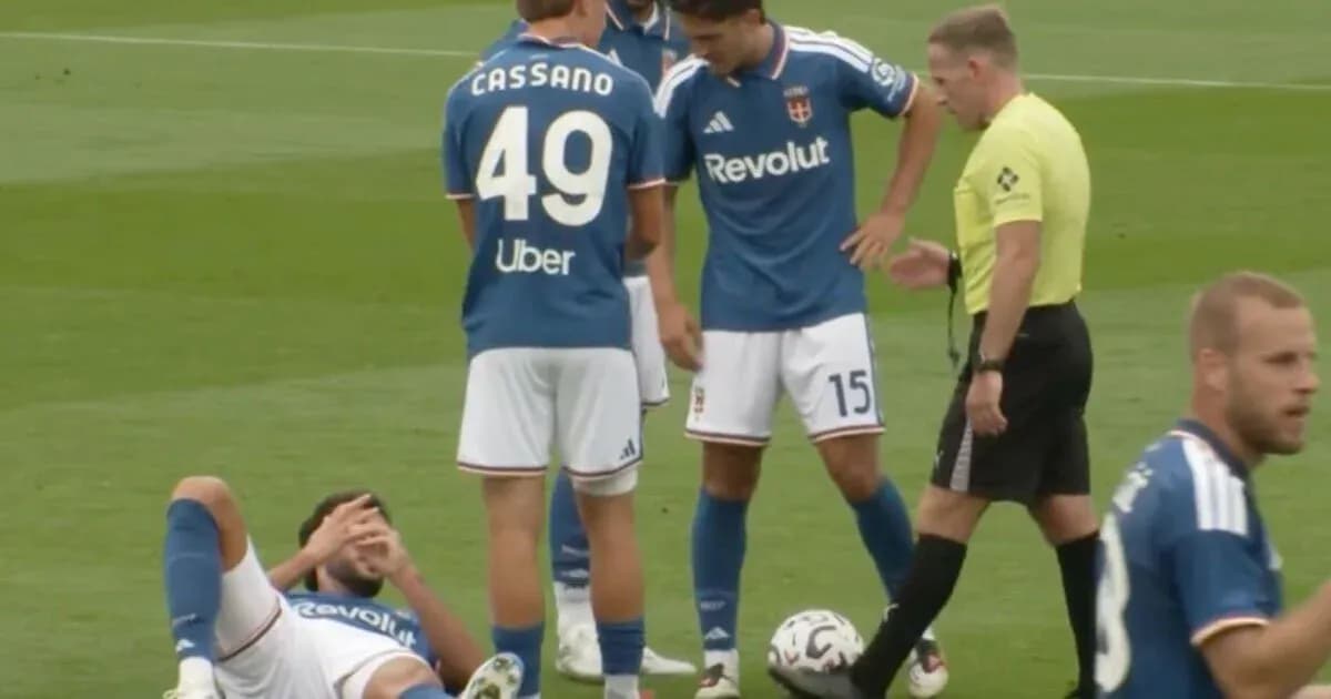 Player lying on ground with teammates and referee nearby