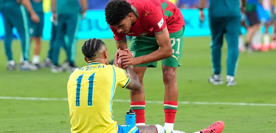 Moroccan player helping Brazilian player on field