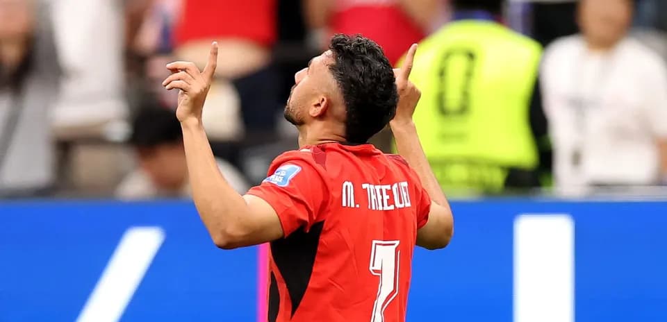 Player celebrating goal with arms raised in stadium