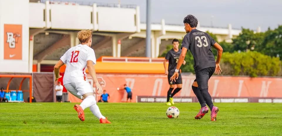 Player in white chasing ball held by player in black