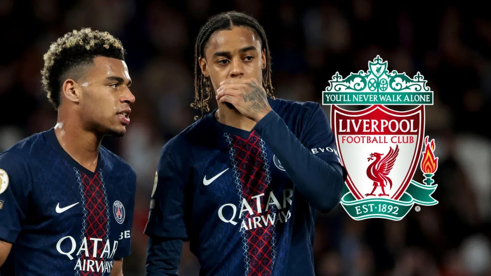Two players discussing during a match with Liverpool logo