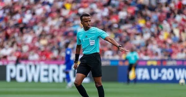 Referee officiating match with players in background