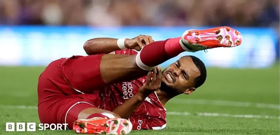 Player in red jersey lying on ground in pain