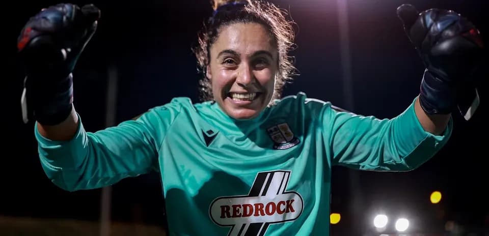 Goalkeeper celebrating with raised fists at night