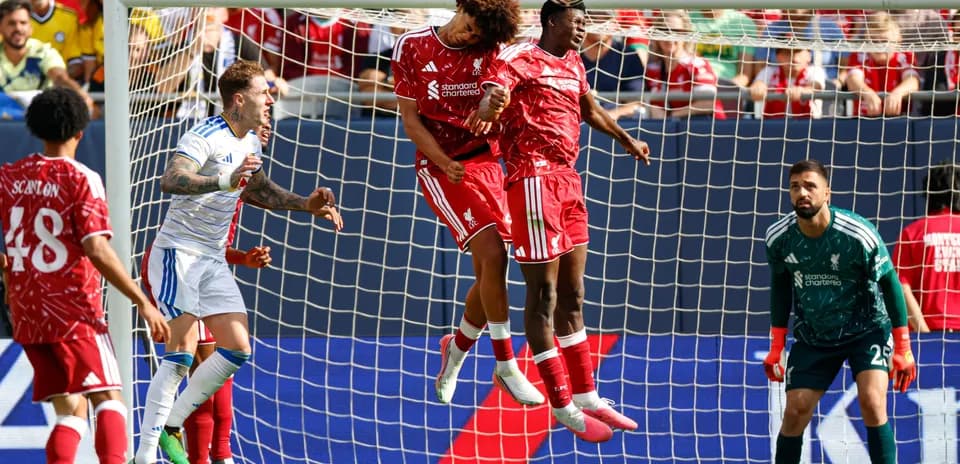 Two Liverpool players jumping to header a ball