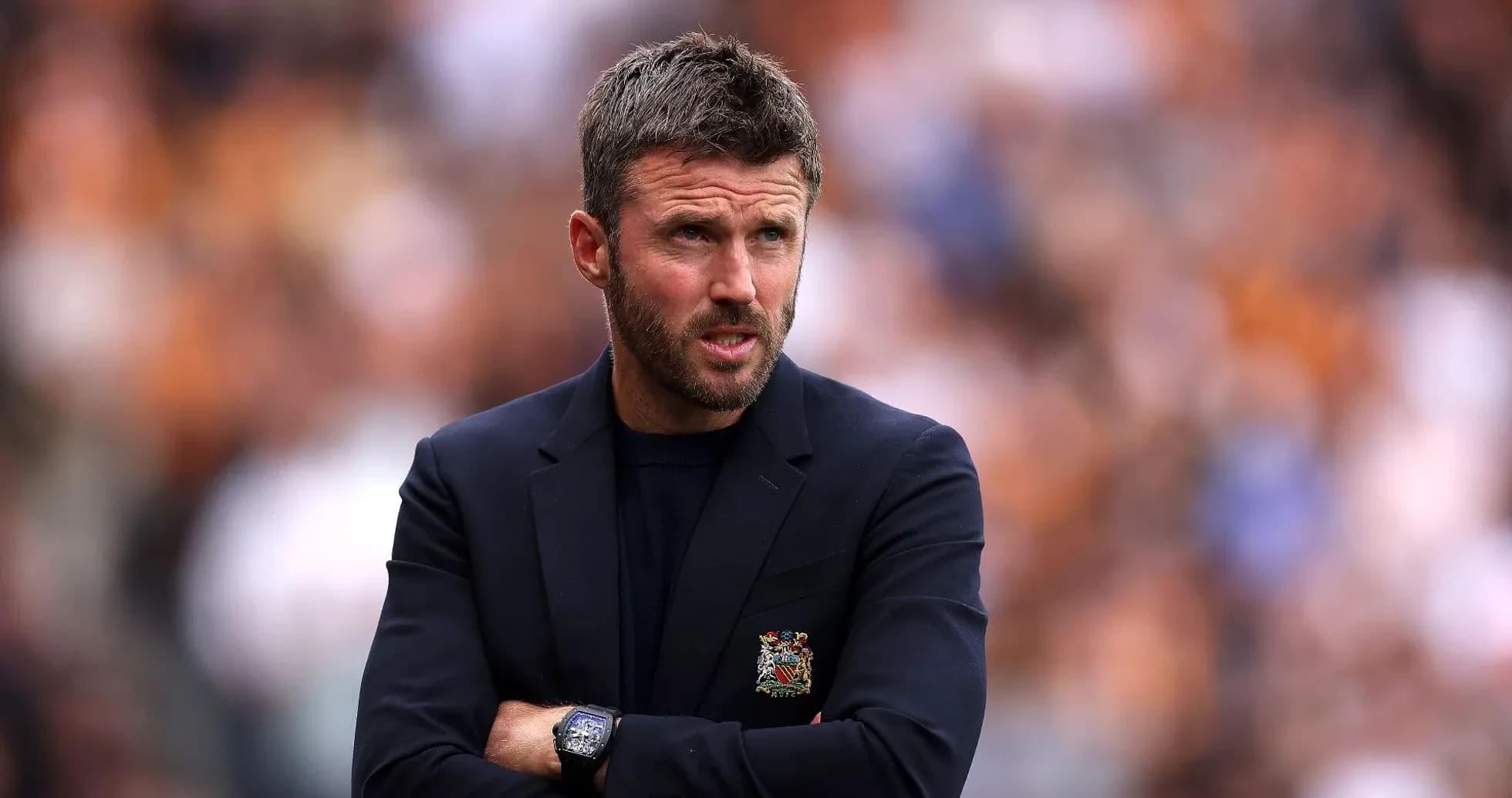 Manager observing match with arms crossed on sideline