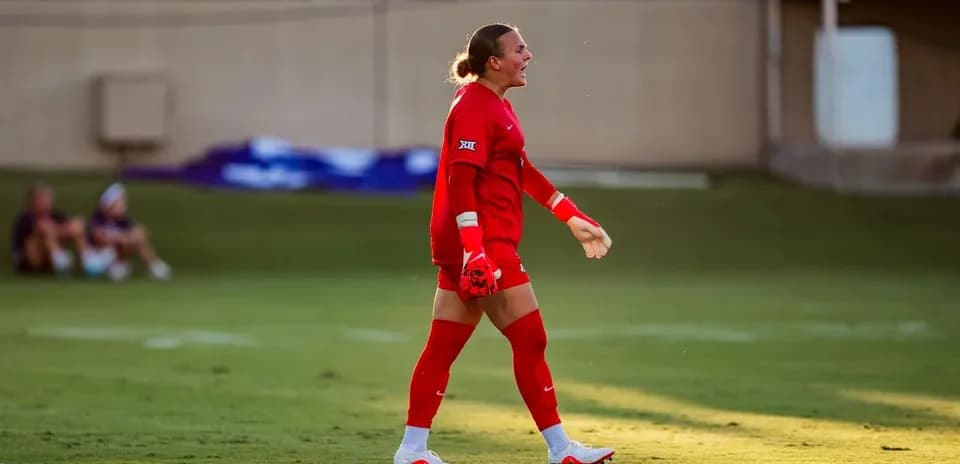 Goalkeeper in red uniform walking on the field