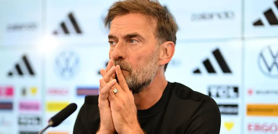 Manager at press conference with hands clasped