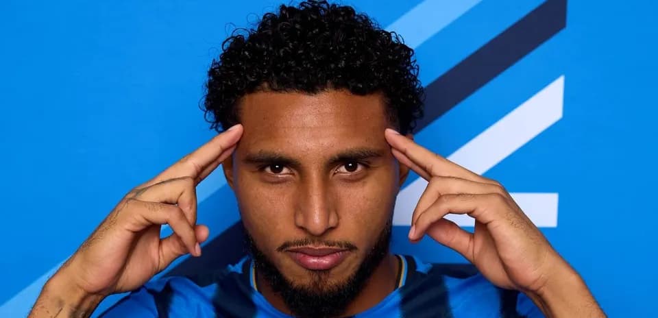Player posing with hands on forehead against blue background