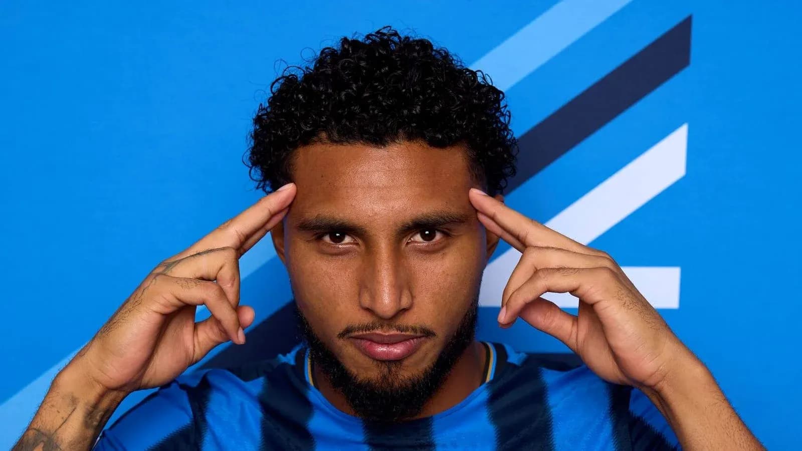 Player posing with hands on forehead against blue background