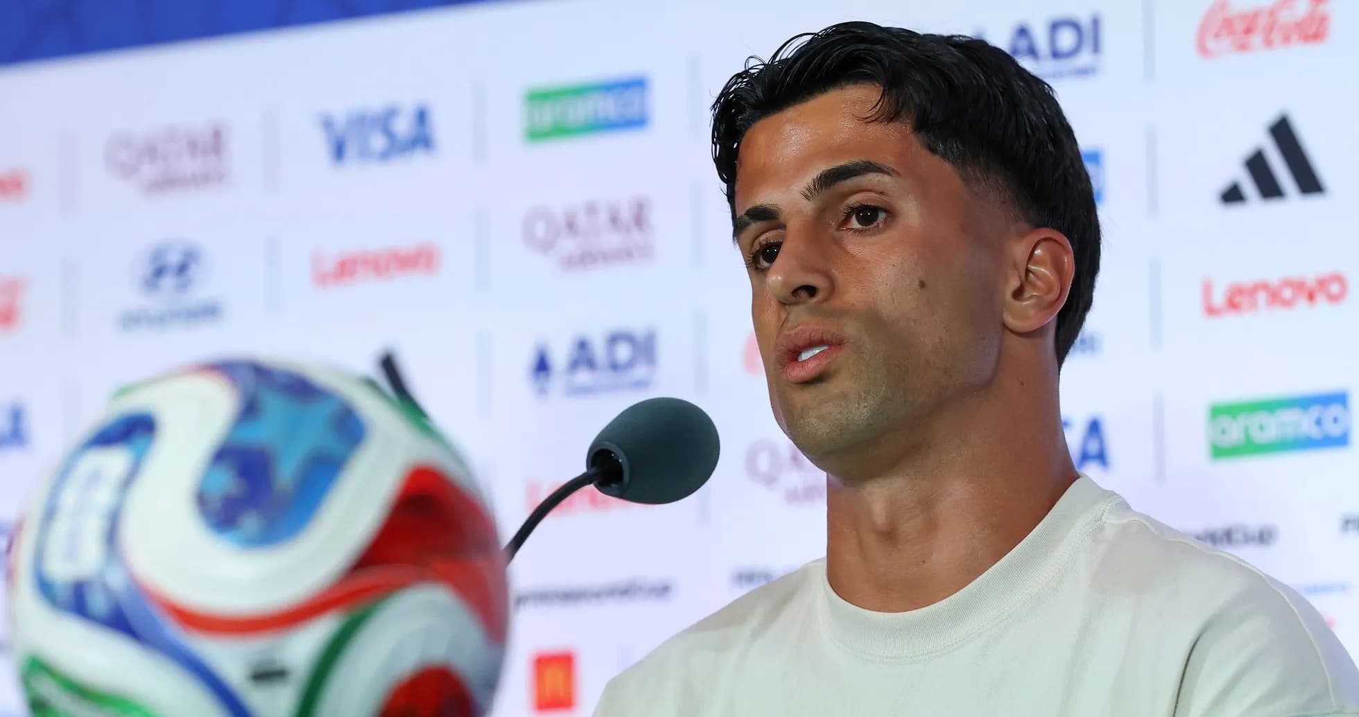 Player speaking at press conference with soccer ball