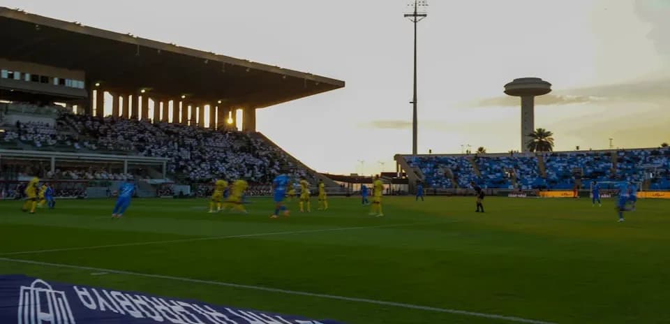 Players in blue and yellow competing during sunset match