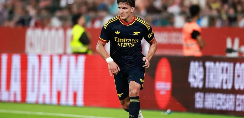 Player in Arsenal kit dribbling the ball on pitch