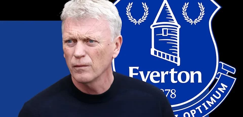 Manager standing in front of Everton club logo