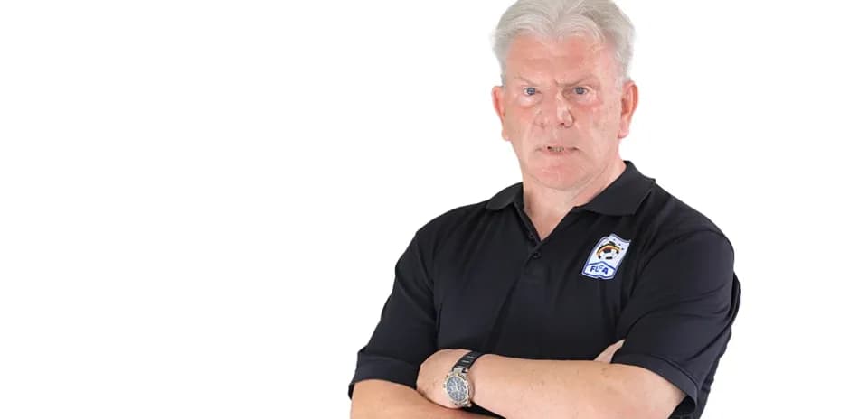 Coach posing with arms crossed in black polo