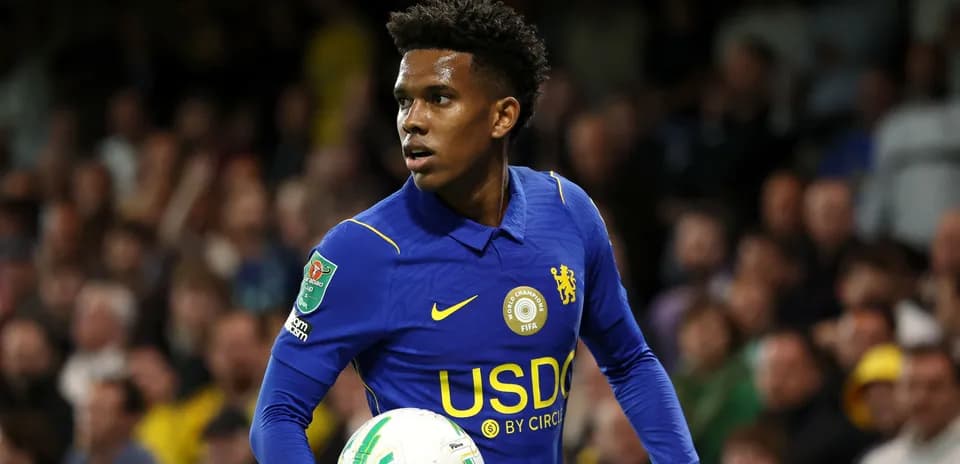 Player in blue jersey holding a football on pitch
