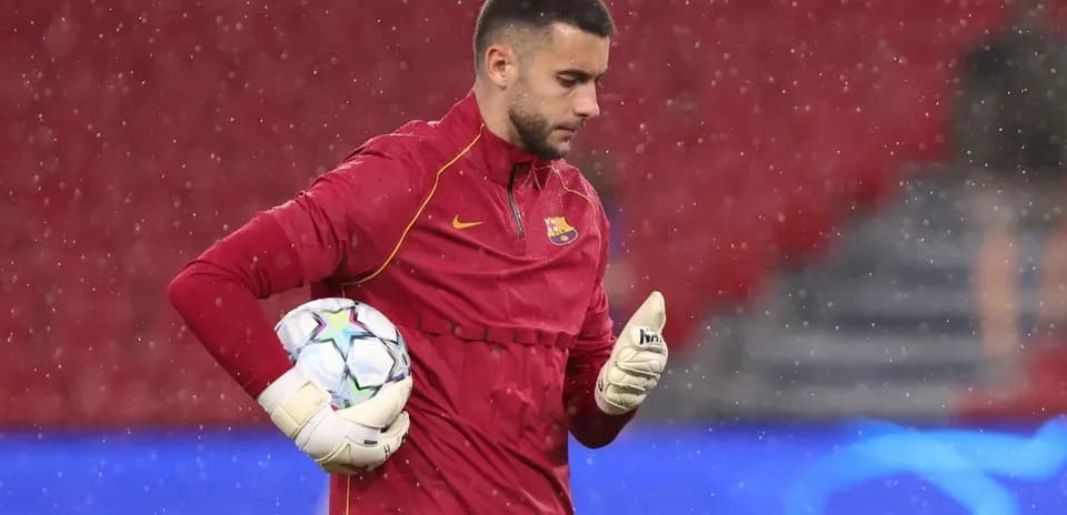 Goalkeeper in red uniform holding a football during training