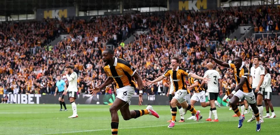 Player celebrating goal with teammates in crowded stadium