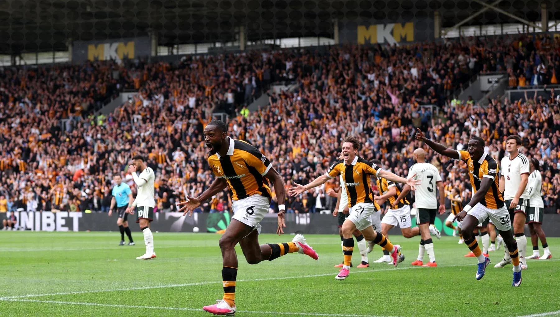 Player celebrating goal with teammates in crowded stadium
