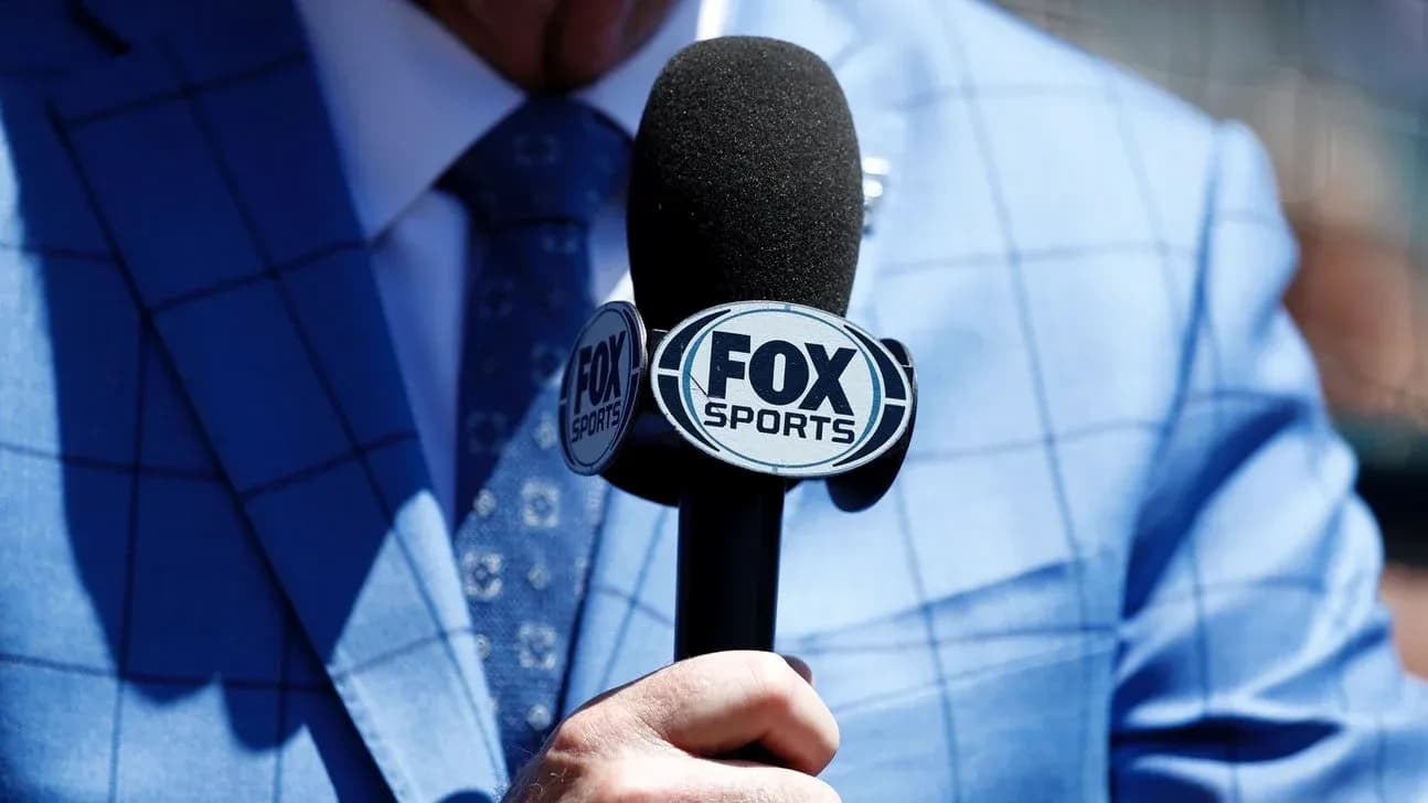 Person holding a FOX Sports microphone in suit